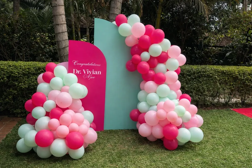 Custom photo backdrop framed by a balloon arch at a celebration setup