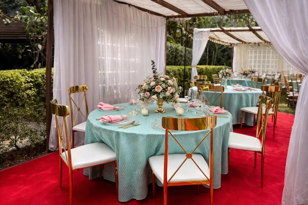 Outdoor garden wedding dining setup in mint and pink linen with floral centrepieces and covered chairs