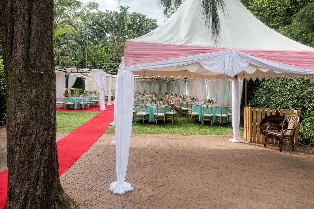 High peak tent at a garden wedding venue with a red carpet walkway and draped entrance