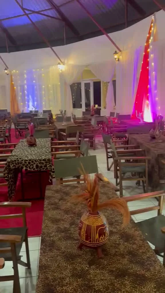 Leopard-print table linen with a hand-painted clay pot centrepiece holding dried grass plumes and a red feather accent